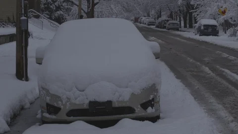 Snow covered parked car with activity in background 動画素材 87478230