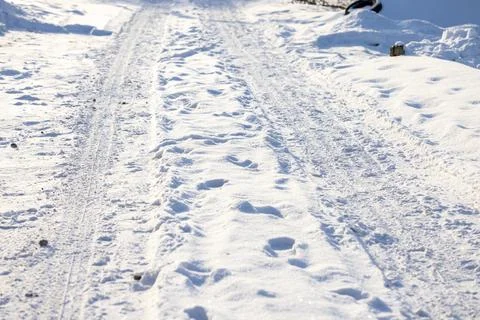 Snow covered path featuring tire tracks and footprints Stock Photos