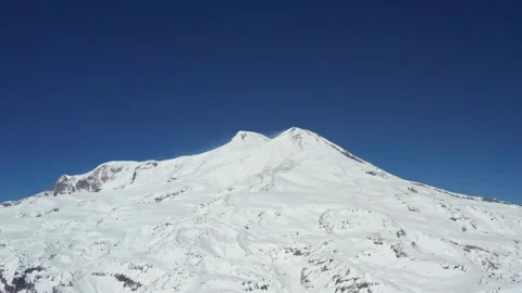 Snow-covered peak of Mount Elbrus under a clear blue sky, showcasing pristine 動画素材 309630653