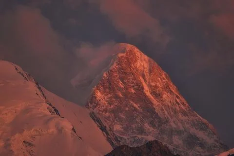 The snow-covered peak of Mount Khan Tengri in Kazakhstan lit by a dramatic re Stockfoto's
