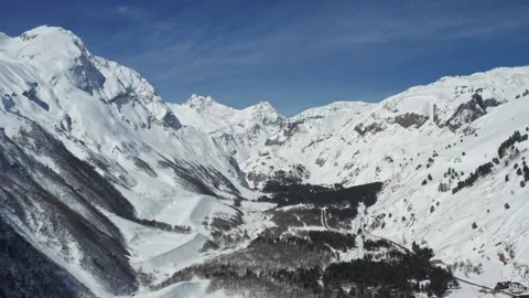 Snow-covered peaks of Mount Elbrus region with a winding road through a serene Stock Footage 309519744