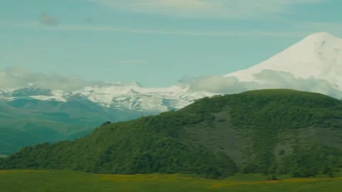 Snow-covered peaks tower over verdant hills, showcasing natures beauty in a 動画素材 312516680