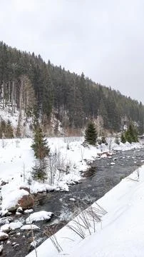 A snow-covered river flows through a wintery forest Snow White mountain Stock Photos