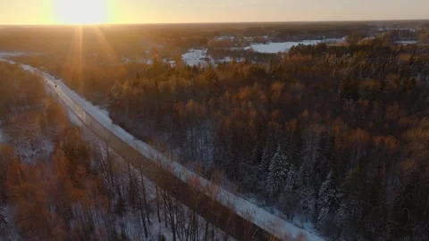 Snow Covered Road Through Forest at Sunset with Frozen Water Stock Footage 300506497