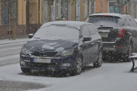 Snow-covered road, wheel marks in the snow and snow-covered cars during heavy Stock Photos