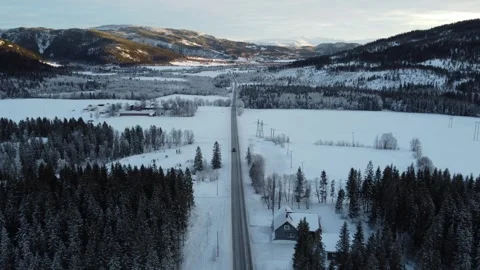 Snow-covered road winding through mountains and trees in winter landscape Stock Footage 328191734