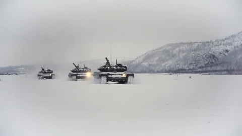 Snow-covered shooting range field in the highlands. Three tracked tanks go after Stock Footage 115861533
