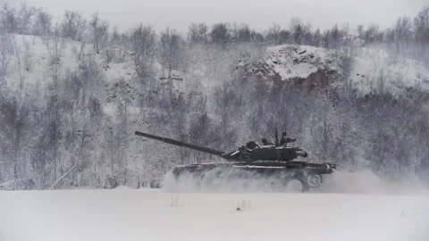 Snow-covered shooting range field in the highlands. The tank rides on the field Stock Footage 146798231