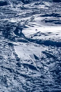 Snow Covered Ski Slope Texture with Tracks and Patterns Under Bright Sunlig.. Stock Photos