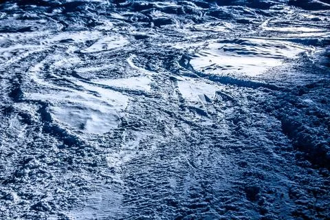 Snow Covered Ski Slope Texture with Tracks and Patterns Under Bright Sunlig.. Stock Photos