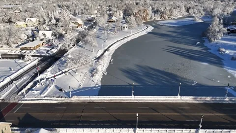 Snow Covered Small Town River and Bridge Aerial Stock Footage 323865288