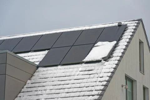 Snow covered solar panel blocking energy production on winter rooftop Stock Photos