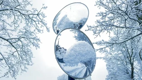 Snow-covered spherical road mirror in winter with trees in the background Stock Footage 298563051