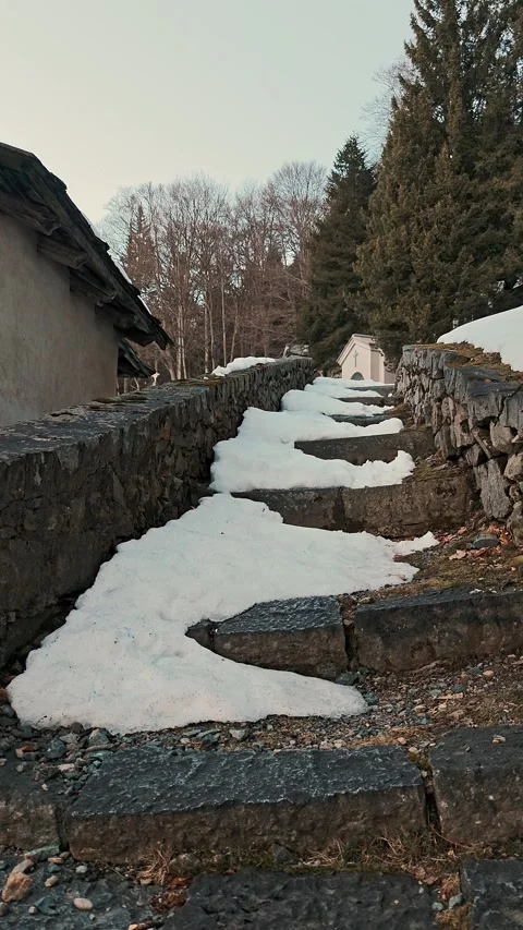 Snow-covered stone steps lead up a path along an old wall near a historical site Video stock 329305465