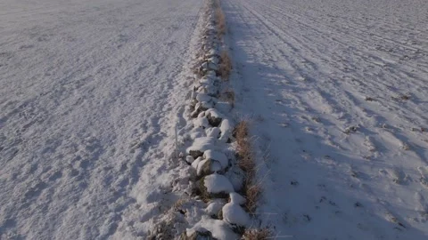 Snow covered stone wall between two fields on the Swedish countryside at sunrise Stock Footage 146808165