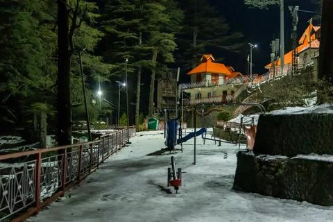 Snow covered temple complex with empty playground at night in hill station Stock Photos