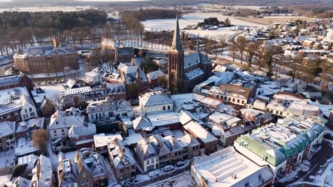 Snow covered town with gothic church steeple and dense rooftops aerial view 動画素材 327990053