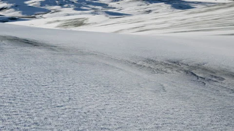 Snow covers the landscape with ridges and patterns under a clear sky Vidéo 340212918