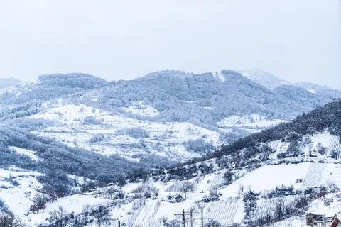 Snow covers mountains and fields in a winter landscape during the day in an.. Stock Photos