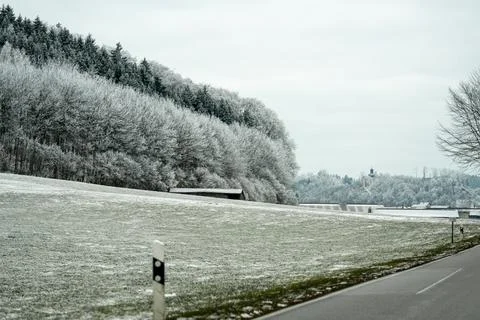 Snow covers trees and fields beside a road in a quiet area near a building .. 库存照片