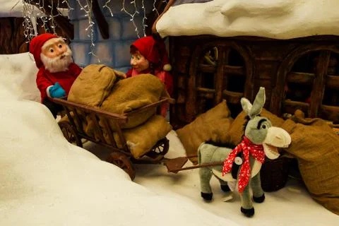 In the snow, a donkey pulls a cart loaded with grain, and grandma and grandfa Stock Photos