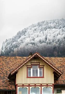 Snow-dusted mountain behind charming house Stock Photos