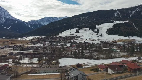 Snow-dusted mountains frame a quiet village below Stock Footage 344753074