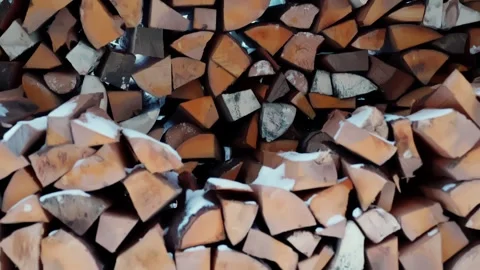 Snow-dusted split logs stacked in a rural woodshed, classic homestead firewood Stock Footage 327690550