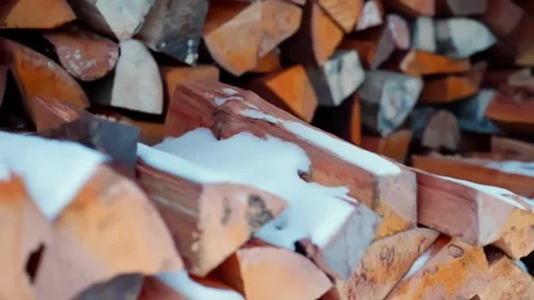Snow-dusted split logs stacked in a rural woodshed, classic homestead firewood Stock Footage 327892165