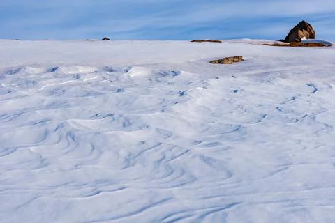 Snow eroded by the action of the wind, also called Sastrugi, on a hill in the Stock Photos
