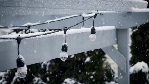 Snow fall on a back yard patio with string lights during a cold winter Stock Footage 148249603