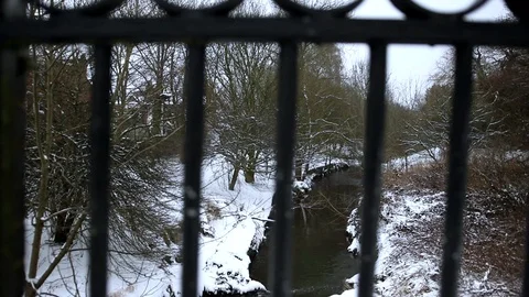 Snow Fall near Stream Through Bars On Park Bridge pan Left to right Stock Footage 90265730