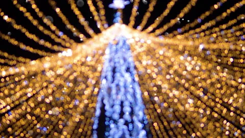 Snow is falling, in the background in defocus are the burning lights of a d.. Stock Footage 230277143
