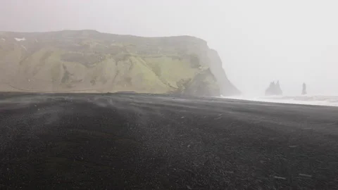 Snow Falling Onto Black Sand Beach With Sea Stacks And Mountain Stock Footage 182153422