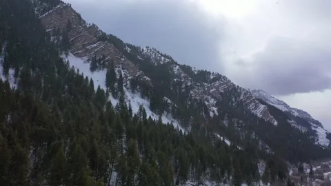 Snow falling in drone shot flying by mountain side Provo Canyon Utah in winter Video stock 168703164