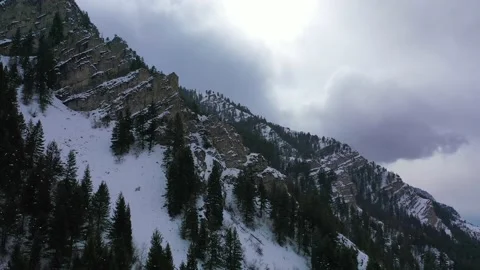 Snow falling in drone shot flying by mountain side Provo Canyon Utah in winter Stock Footage 168703301