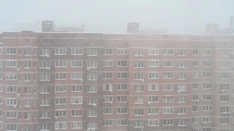 Snow falling on the facade of a brick apartment building Видео 283983731