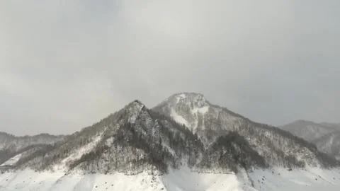 Snow falling by a large mountain in winter landscape Stock Footage 272893218