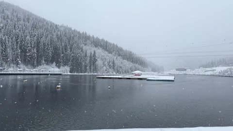 Snow falling on mountain lake with docks Stock Footage 294111606