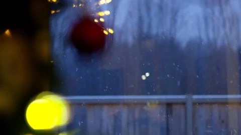 Snow falling outside window with christmas tree ornaments close up in Stock Footage 115286190