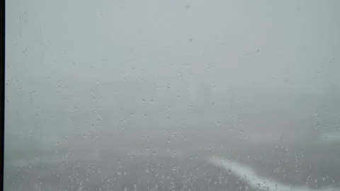 Snow is falling outside the window. Water droplets on the window pane. Видео 325985025
