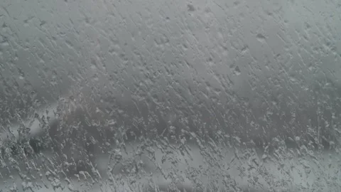 Snow is falling outside the window. Water droplets on the window pane. Видео 325985066