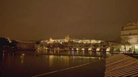 Snow falling over Charles Bridge and Prague Castle at night Stock Footage 333379451