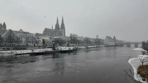 Snow falling over Danube River cathedral and stone bridge in Regensburg Germany Stock Footage 327454010