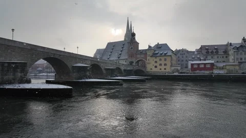 Snow falling over Danube River cathedral and stone bridge in Regensburg Germany Stock Footage 327454155
