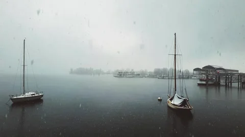 Snow falling over maggiore lake, moored boats and ferryboats panning Stock Footage 278961829