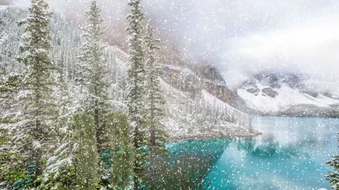 Snow Falling Over Turquoise Mountain Lake and Evergreen Forest in Winter Stock Footage 222033916