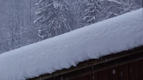 Snow falling peacefully on a snow-covered wooden roof. Stock Footage 222899013