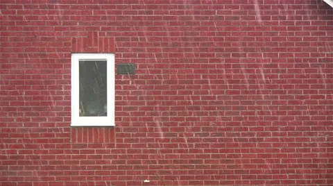 Snow falling on red brick background with white framed window Stock Footage 35056090