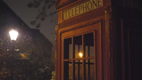 Snow falling on a red telephone booth and a street lantern at night. Stock Footage 101704249